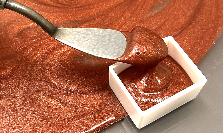 パレットナイフでミニパンに詰められるラメ入りの創作水彩絵具(赤銅色)